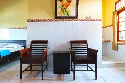 two chairs and a table in a room with a bed at Gora Beach Inn in Kuta
