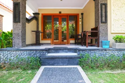 a front door of a house with a stone wall at Gora Beach Inn in Kuta