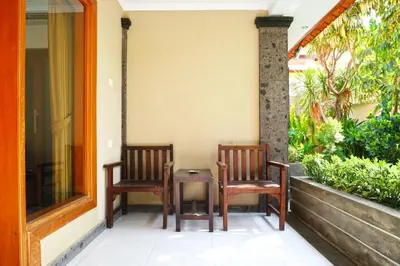 two chairs and a table on the porch of a house at Gora Beach Inn in Kuta