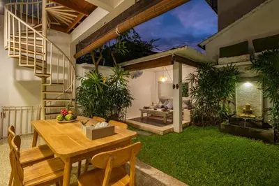 a patio with a table and chairs and a garden at 3 Bedroom cozy private pool Villa in Seminyak WIFI in Seminyak