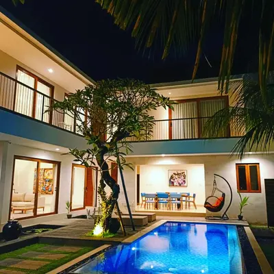 a villa with a swimming pool in front of a house at Villa Dharmatria in Nusa Dua