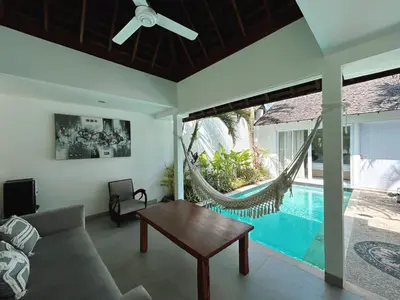 a living room with a couch and a hammock next to a pool at Astana Villas in Seminyak