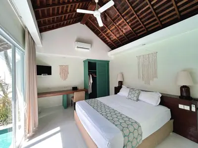 a bedroom with a bed and a ceiling fan at Astana Villas in Seminyak