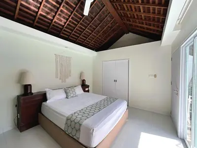 a bedroom with a large bed and a wooden ceiling at Astana Villas in Seminyak