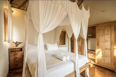 a bedroom with a canopy bed with white curtains at Villa Umah Maya 3BR Seminyak in Seminyak