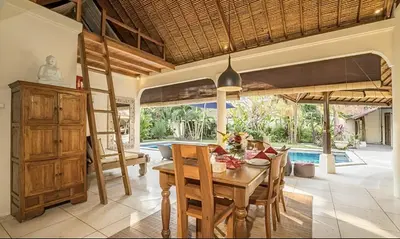 a dining room with a wooden table and chairs at Villa Umah Maya 3BR Seminyak in Seminyak