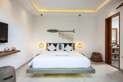 a bedroom with a white bed and a tv at Spectacular 4BR Villa, 400m to Beachfront Bliss in Canggu