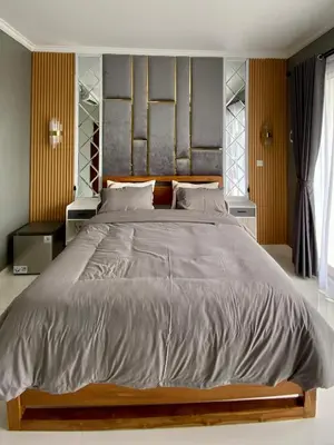 a bedroom with a large bed with a wooden headboard at Melza Room no 4 in Kerobokan
