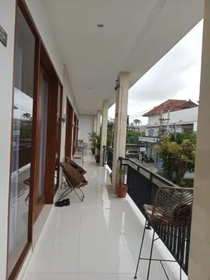 a balcony with chairs and tables on a building at Melza room no.3 in Kerobokan