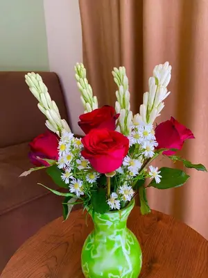 a green vase with red roses and white flowers at Melza room no.3 in Kerobokan