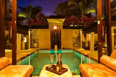 a swimming pool with a bottle and glasses on a table at Villa One Seminyak in Seminyak