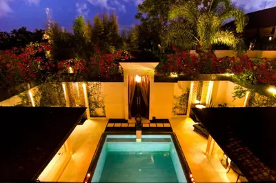 a swimming pool with benches and flowers on a house at Villa One Seminyak in Seminyak