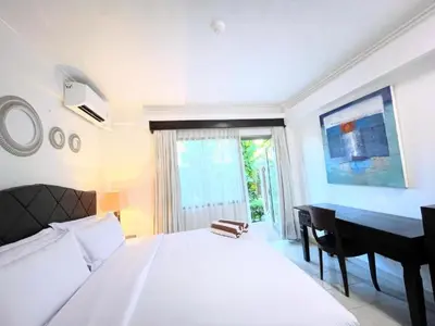 a bedroom with a white bed and a desk and a bed sidx sidx at Suite Hotel Apartment Legian by RCP in Seminyak