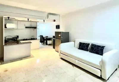 a living room with a white couch and a kitchen at Suite Hotel Apartment Legian by RCP in Seminyak