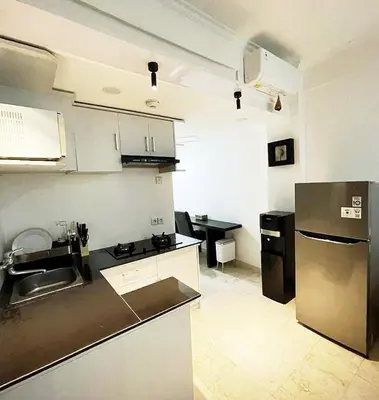 a kitchen with a sink and a refrigerator at Suite Hotel Apartment Legian by RCP in Seminyak