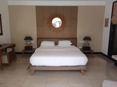 a bedroom with a large bed with two tables and a mirror at Villa Samatha in Nusa Dua