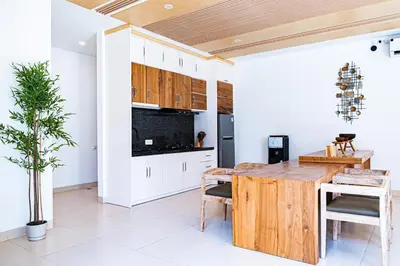 a kitchen with white cabinets and a wooden table at La Boutique Lux's Villas Seminyak Bali in Seminyak