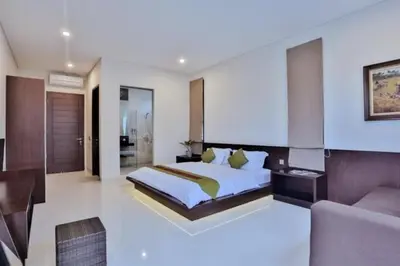a large bedroom with a bed and a couch in it at The Arnaya in Kuta