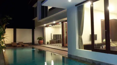 a house with a swimming pool next to a building at The Arnaya in Kuta