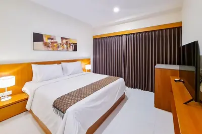 a bedroom with a large bed and a television at Aldan Guest House Syariah in Pesanggaran
