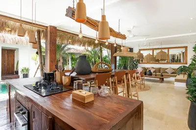 a kitchen and living room with a counter and chairs at Villa Senya - Bali Bliss 3BR Mediterranean Escape with Private Pool, Stylish Retreat Between Seminyak & Canggu in Kerobokan