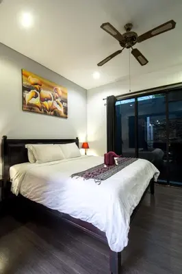a bedroom with a large bed with a ceiling fan at Villa cinta buana 1 in Legian
