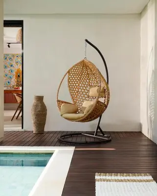 a wicker swing chair in a living room next to a pool at Villa Ananya Seminyak by Nakula in Seminyak