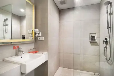 a white bathroom with a sink and a shower at Kuta Galleria Hotel in Kuta