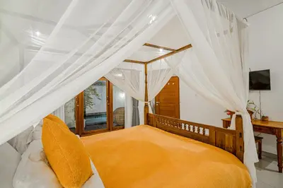 a bedroom with a canopy bed with white curtains at Villa Miamara by Bali Villa Solutions in Seminyak