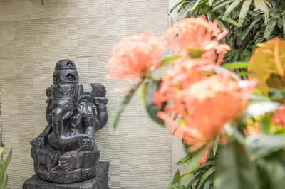 a statue of a deity next to some flowers at Villa Seriska Seminyak, 5-Star Private Pool Villa, Walk to Dining & Shopping in Seminyak