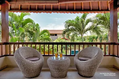 two chairs and a table on a balcony with palm trees at Villa Seriska Seminyak, 5-Star Private Pool Villa, Walk to Dining & Shopping in Seminyak