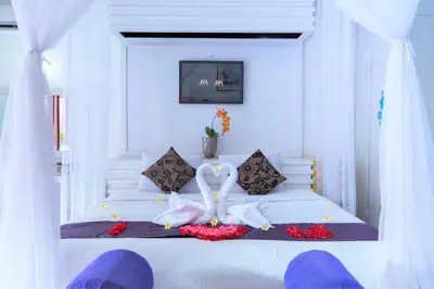 a bedroom with a white bed with two swans on it at Romantic Private Villas Kuta Bali in Kuta