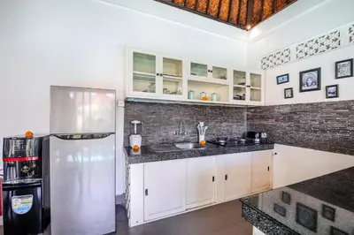 a kitchen with white cabinets and a stainless steel refrigerator at Villa Anouk in Seminyak
