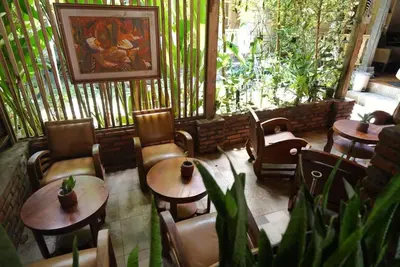a restaurant with wooden tables and chairs and plants at Oma Joglo Jimbaran in Jimbaran