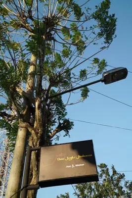 a tree with a sign next to a street light at Oma Joglo Jimbaran in Jimbaran
