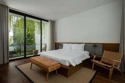 a bedroom with a bed and a chair and a window at Villa Talisman - Luxury Rooftop Canggu Villa Only 5 mins to Beach in Canggu