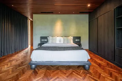 a bedroom with a large bed and wooden floors at Casa Madi Canggu in Canggu