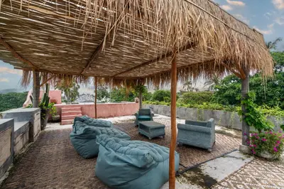 a patio with chairs and a straw umbrella at Casa Madi Canggu in Canggu