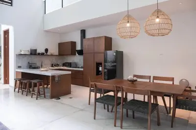 a kitchen with a wooden table and chairs and lights at Villa Talisman - Stylish Canggu with Rooftop Villa 5 mins to Beach in Canggu