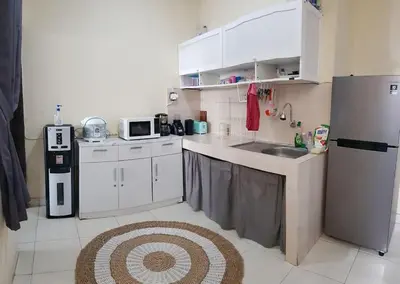 a kitchen with white cabinets and a sink and a refrigerator at Laura Dewi House in Jimbaran