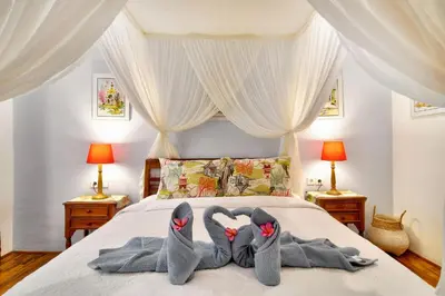 two pairs of slippers and towels on a bed at Selasih Beach House in Seminyak