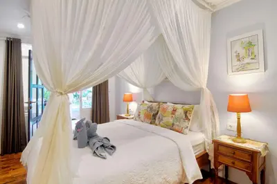 a bedroom with a white canopy bed with a teddy bear on it at Selasih Beach House in Seminyak