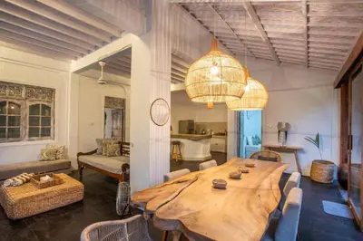 a living room with a large wooden table and a chandelier at Villa Dolcevita Seminyak in Seminyak