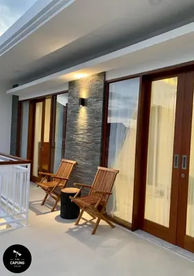 a balcony with two rocking chairs and glass doors at Capung Smart Residence in Sanur