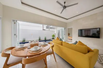 a living room with a table and a yellow couch at The Eclipse Villas - The Luxurious 2BR Private Pool Canggu Getaway in Canggu