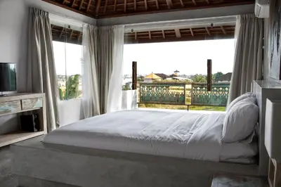 a bedroom with a large bed and a large window at Surflodge Limasan Bali in Kerobokan