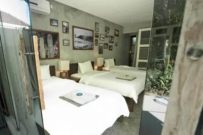 a room with three beds with white sheets at Surflodge Limasan Bali in Kerobokan