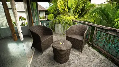 a patio with two chairs and a table and a fence at Surflodge Limasan Bali in Kerobokan