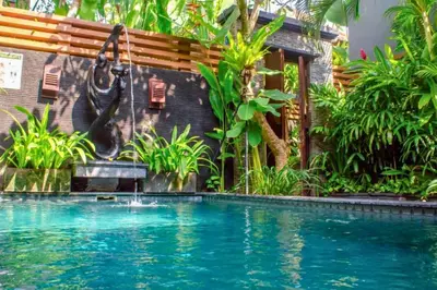 a swimming pool in a garden with a swing at Swaran 1 BR Private Pool Villa in Seminyak