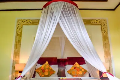 a canopy bed with white curtains and pillows at Swaran 1 BR Private Pool Villa in Seminyak